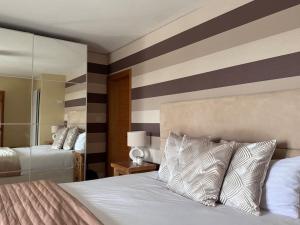 a bedroom with two beds and a striped wall at Green Acres House in Horspath +36 photos