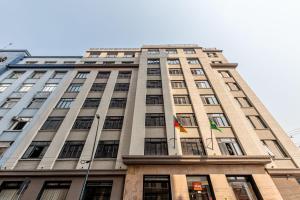 a tall building with two flags on it at Xtay Cais Rooftop - Estúdios Completos com Wifi e academia, no Centro Histórico de Porto Alegre in Porto Alegre