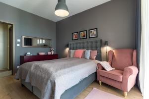 a bedroom with a bed and a pink chair at Lake Side Luxury Steps To The Lake Lela - Happy Rentals in Balatonlelle