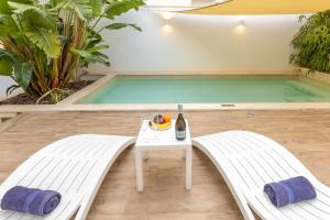 a pool with two benches and a table in front of it at Modern Beautiful Pool And Sea Apt Qawra - Happy Rentals in Qawra