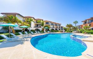 a swimming pool with chairs and umbrellas in a resort at Beach Living at Sunrise to Sunset Villa in West Bay