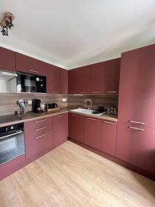 a large kitchen with red cabinets and a sink at Duplex le Brooklyn en Plein centre de Mordelles in Mordelles +29 photos