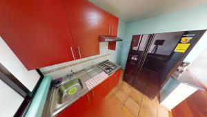 eine Küche mit roten Schränken und einem Herd und einem Kühlschrank in der Unterkunft Bello departamento en Centro Histórico de la CDMX in Mexiko-Stadt