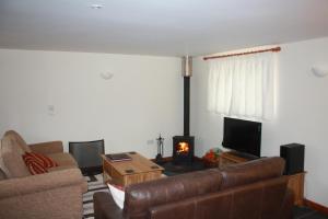 a living room with a couch and a fire in the fireplace at The Byre in Wellington
