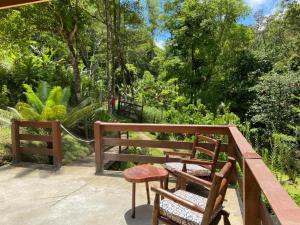 a wooden balcony with two chairs and trees at casa dos klein in Nova Friburgo