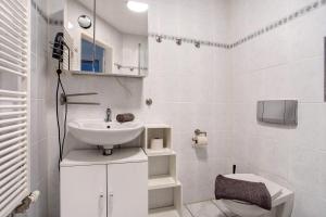 a white bathroom with a sink and a toilet at Bäckerhus - Ferienwohnung 5 in Wiek auf Rügen 