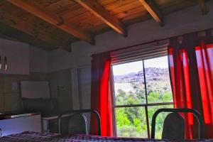 Habitación con ventana grande con cortinas rojas. en Complejo Salamanca - Cabaña La Catalana, en Trapiche