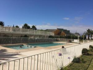 a swimming pool next to a white fence at Apartamento Terrazas del Sol in La Serena