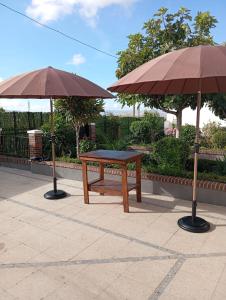 a picnic table and two umbrellas on a patio at Villa Turística Miguel in Pulianas