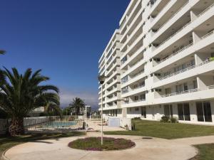 a large white apartment building with a pool and palm trees at Apartamento Terrazas del Sol in La Serena