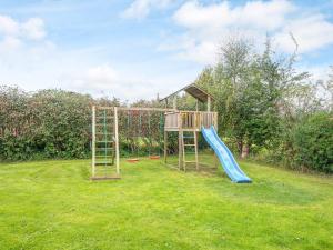 - une aire de jeux avec toboggan dans la pelouse dans l'établissement Luxury Retreat with Pool - By Traum Ferienwohnungen, à Sønderby