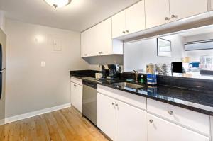 eine Küche mit weißen Schränken und einer schwarzen Arbeitsplatte in der Unterkunft Spacious Apt Downtown in Stamford