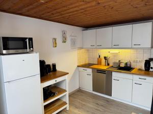 eine Küche mit weißen Schränken und einem weißen Kühlschrank in der Unterkunft Ferienwohnung Linde in Oberstaufen