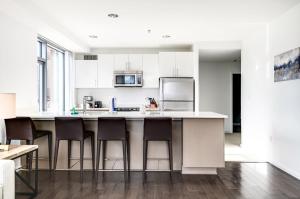 a kitchen with white cabinets and a island with bar stools at Luxury Apt Near Kendall Square in Cambridge