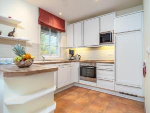 una cocina con armarios blancos y un bol de fruta en la barra en Villa Kormoran, en Dierhagen 24 fotos más
