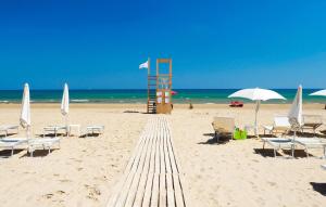 ein Strand mit Liegestühlen und einem Rettungsschwimmerturm und das Meer in der Unterkunft Nice Home In Marina Di Modica in Marina di Modica + 18 Fotos