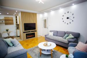 a living room with two couches and a clock on the wall at Queen Deluxe in Sombor