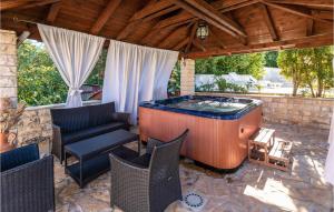 a hot tub on a patio with chairs at Stunning Home In Ston With Sauna in Ston