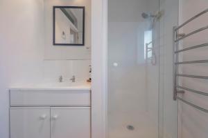 Un baño blanco con lavabo y ducha. en Across the Road to the Beach - Apartment, en Whitianga 14 fotos más