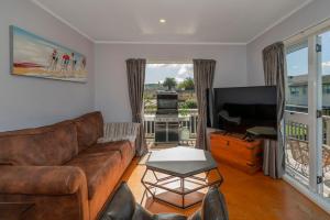 Una sala de estar con un sofá y un televisor de pantalla plana. en Across the Road to the Beach - Apartment, en Whitianga