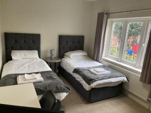 a bedroom with two beds and a desk and a window at Large 4 bed detached house with parking in Newark-on-Trent
