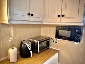a kitchen with a microwave and a toaster oven at Casinha Margarida in Adaúfe