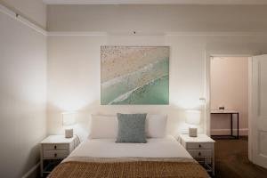 - une chambre blanche avec un lit et 2 tables de chevet dans l'établissement Fenton Cottage, à Hobart