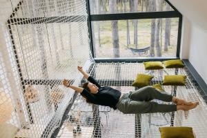 a woman laying on the top of a batting cage at Wyjątkowy domek w kompleksie Patyki Las Możliwości in Zelów