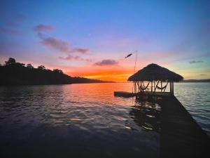 a dock with a hut on the water at sunset at Akwaba Lodge Island Boutique Hotel in The Gap