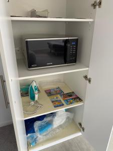 a white cabinet with a microwave on a shelf at 2BD Family or Couple Guesthouse Upstairs near Turf club, HOTA in Bundall in Gold Coast