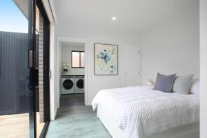 1 dormitorio blanco con 1 cama y lavadora en Three Pines - 300m to town, en Kiama
