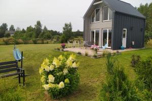 a house with a bench and flowers in the yard at Holiday home with private garden, sauna, jacuzzi in Sieciemin