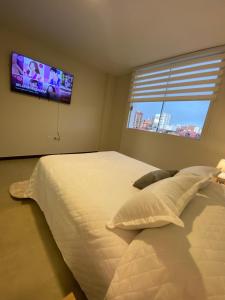 a bedroom with a large bed and a flat screen tv at Departamento en barrio Petrolero in Sucre +28 photos
