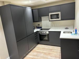 a kitchen with black cabinets and a microwave at Central Leeds - 2 Bed Ensuite in Leeds +18 photos