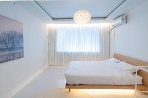 Un dormitorio blanco con una cama y una ventana. en Gangneung station chandelier house 3b, en Gangneung