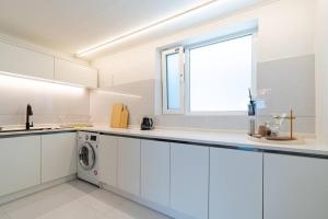 cocina blanca con lavadora y ventana en Gangneung station chandelier house 3b, en Gangneung