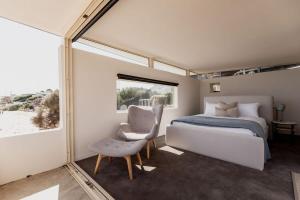 South ArmにあるBeachfront Paradise in Opossum Bayのベッドと椅子と窓のある寝室
