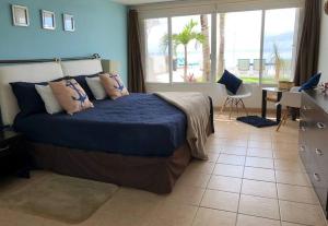 una camera da letto con un letto con lenzuola blu e una finestra di Inspiring and relaxing sea view condo a Cozumel Altre 57 foto