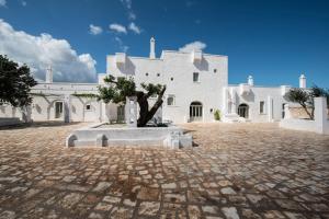 a white building with a tree in front of it at Masseria Le Carrube in Ostuni