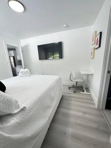 a white bedroom with a bed and a flat screen tv at 5 Star Feel in Miami Prime Location in Miami +18 photos