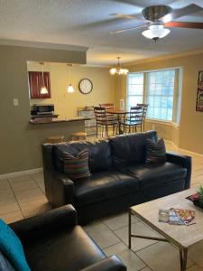a living room with a black couch and a kitchen at 3 bedroom Cozy vacation rental near airport in Kenner