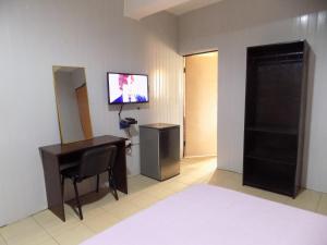 a hotel room with a desk and a tv on the wall at Posh Apartments and Hotel in Ikeja