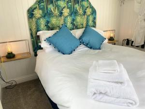 a white bed with blue pillows and towels on it at LB Newgate in Lymington