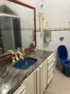 a bathroom with a sink and a mirror and a toilet at Suíte privativa com cama Queen em casa ampla e confortável em casa compartilhada in Palhoça
