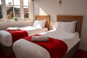 a bedroom with two beds with red and white sheets at Rose and Crown B&B in Burwash