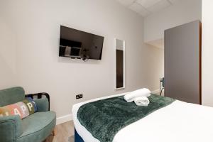 een slaapkamer met een bed, een bank en een tv bij Hyde Park Studios in Londen