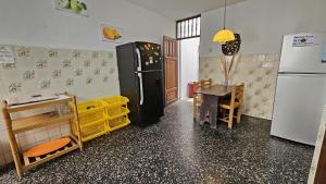 a kitchen with a refrigerator and a table in it at Yellow Surf House in Huanchaco