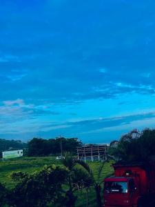 a red truck parked in a field with a fence at Quarto confortável em Imbituba in Imbituba