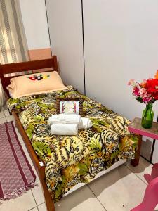 a bed with a leopard print blanket and towels at Quarto confortável em Imbituba in Imbituba