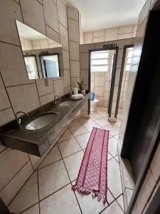 a bathroom with a large sink and a pink rug at Quarto confortável em Imbituba in Imbituba